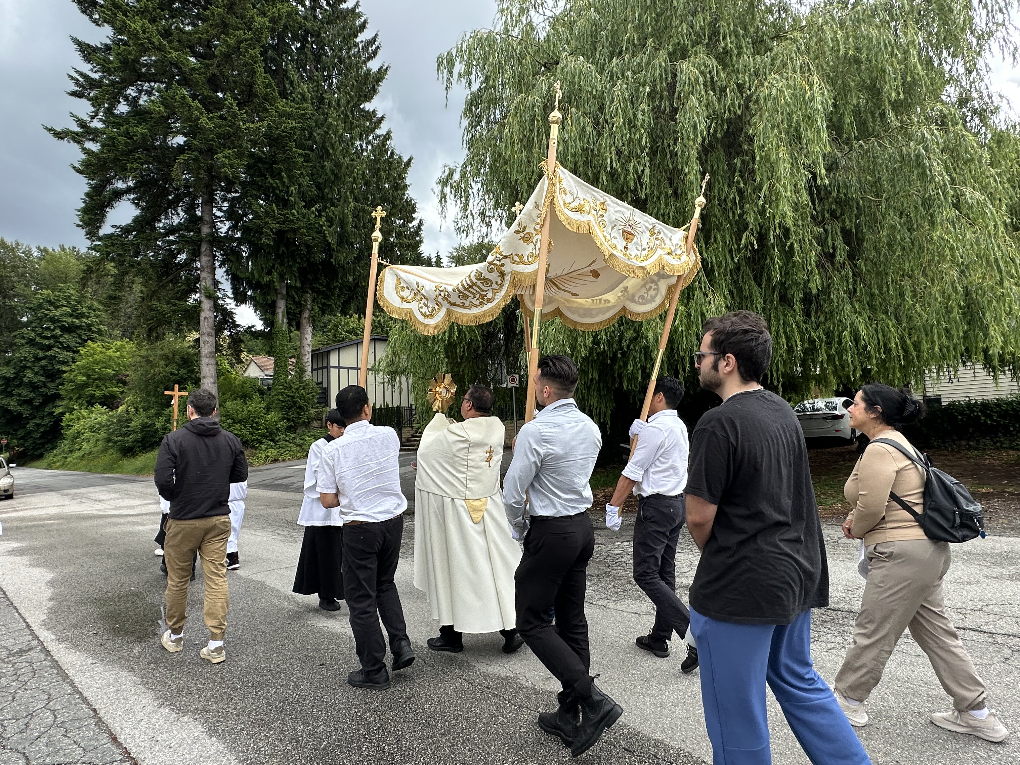 The priest carrying the Blessed Sacrament beneath the canopy during the procession