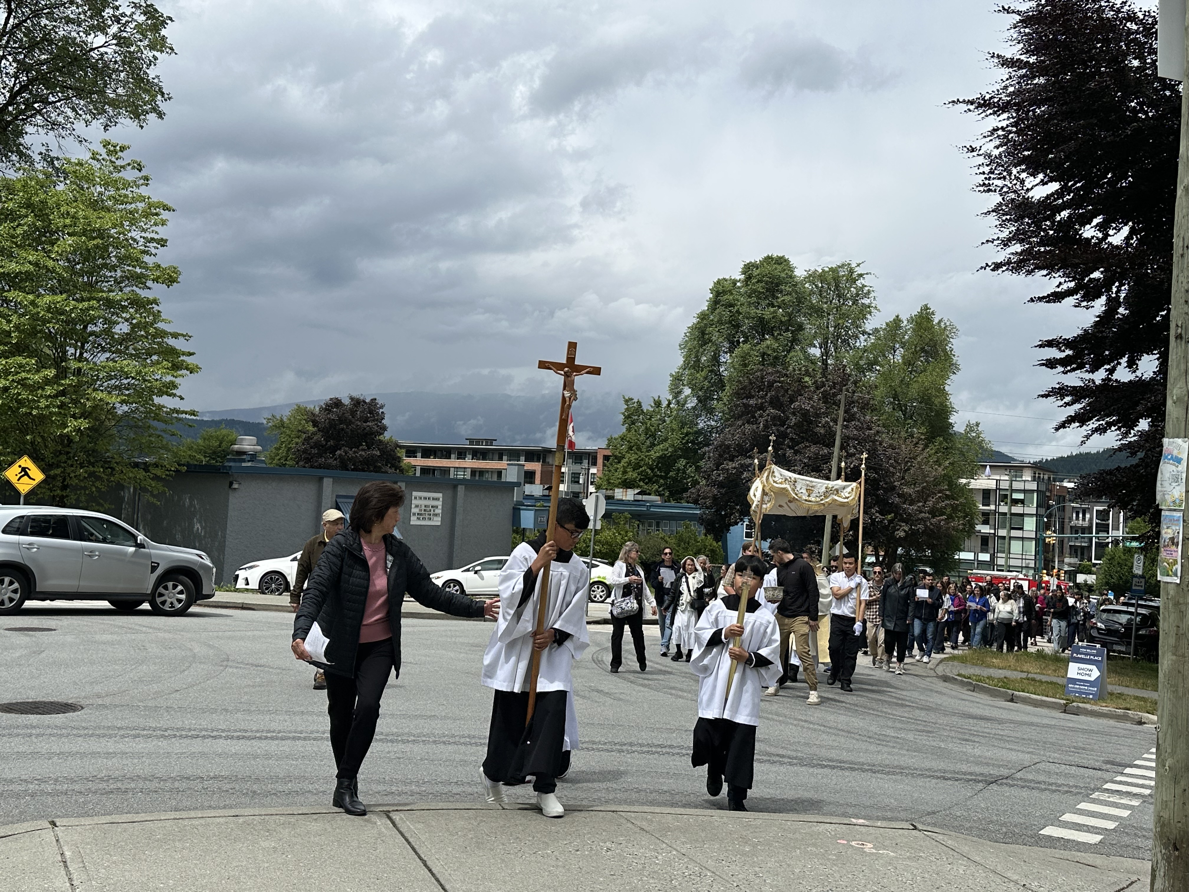 Parishioners joining the Corpus Christi procession beneath dramatic clouds