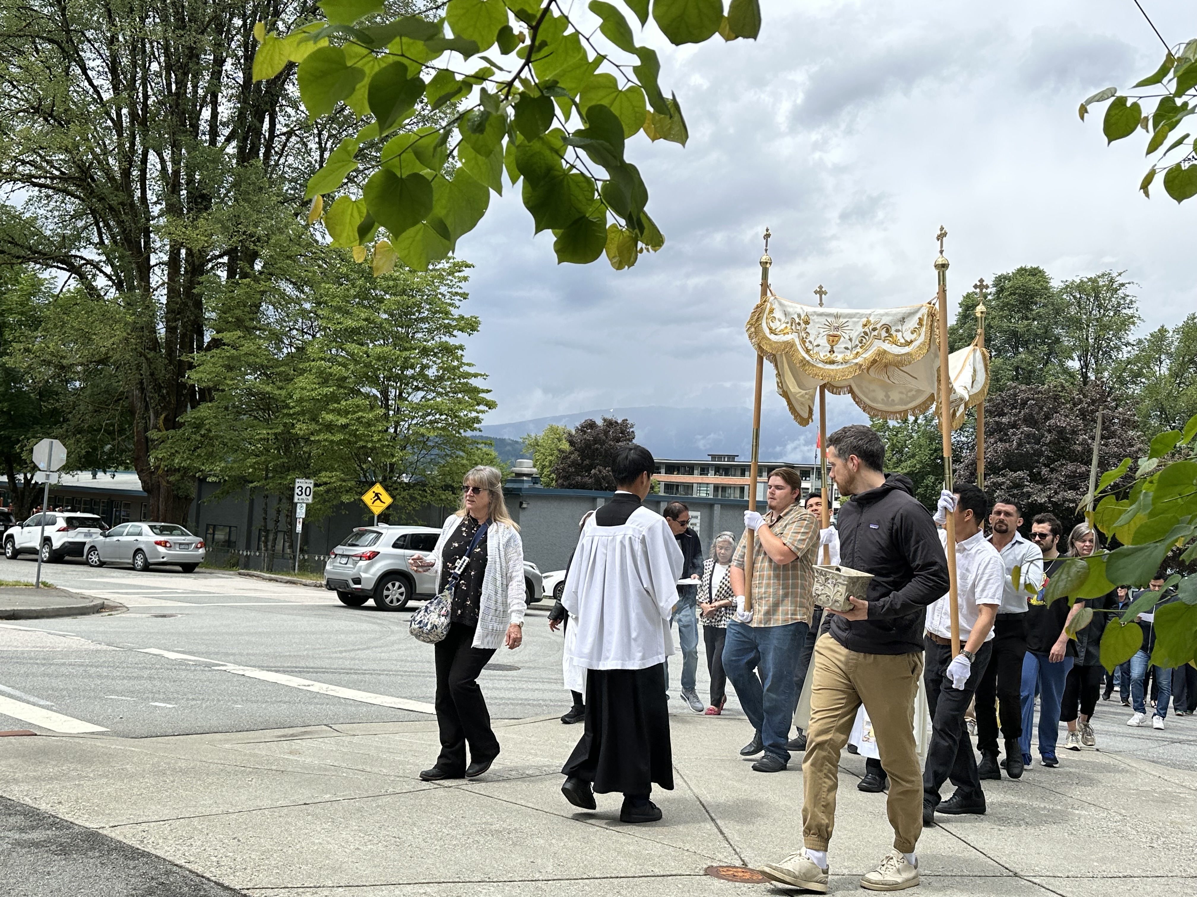 A wide view of the Corpus Christi procession walking uphill in Port Moody