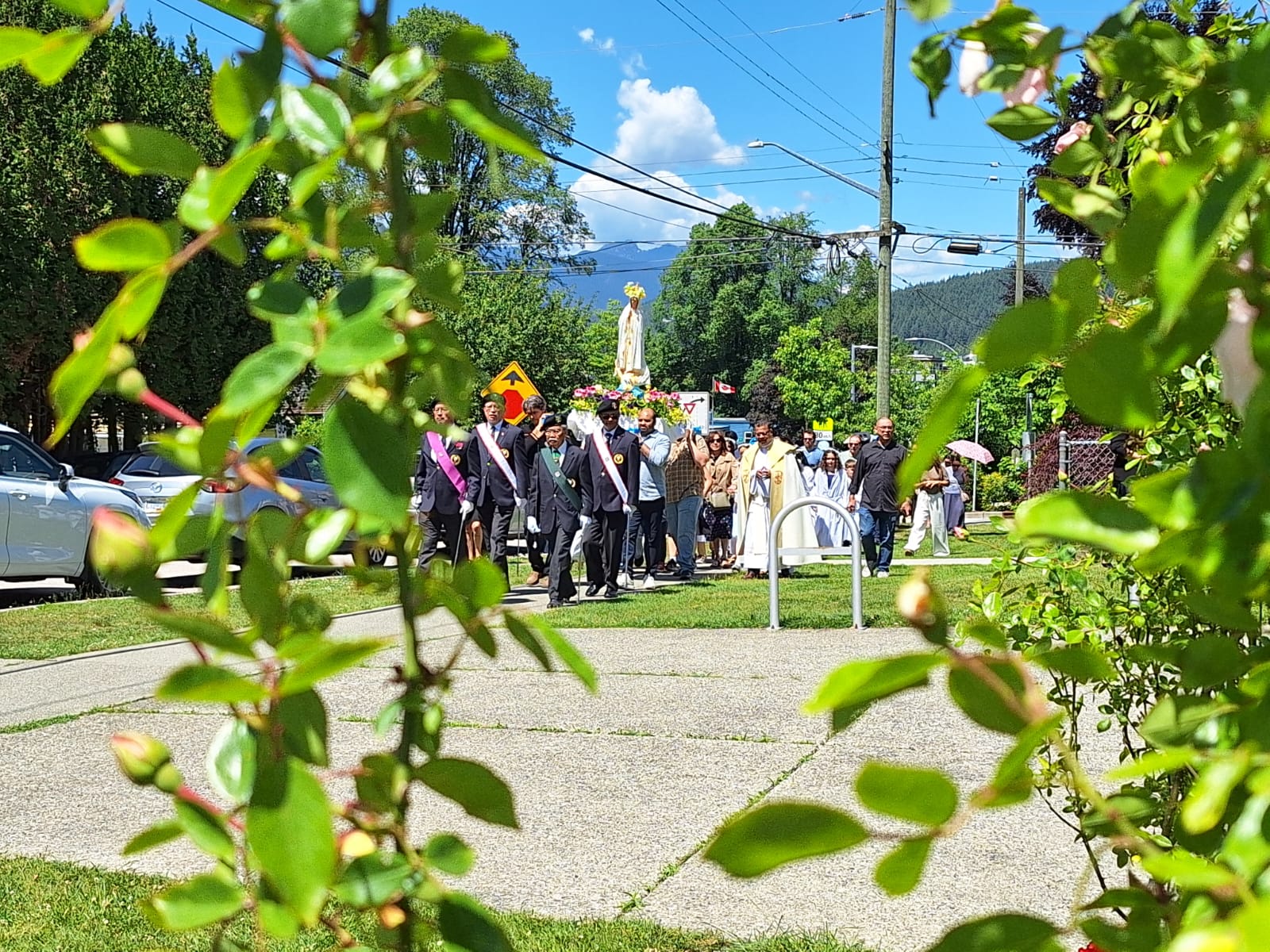 Marian Procession approaching through sunshine and greenery