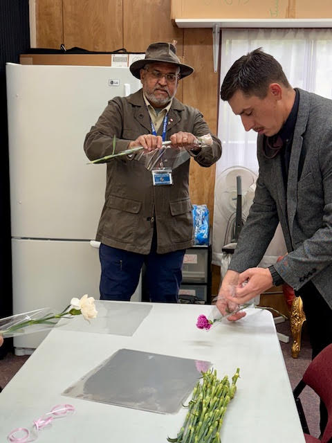 Close-up of a Knight gently placing a carnation in a sleeve